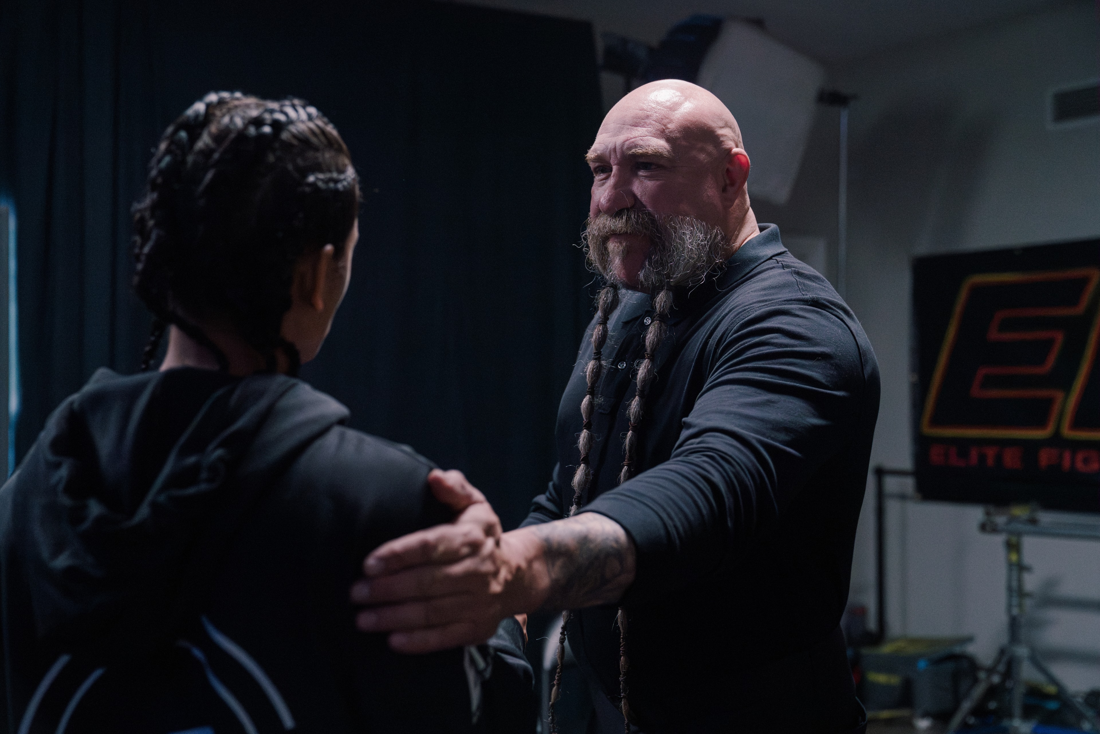 Fighter and trainer preparing in a dark gym setting on The Last Round set